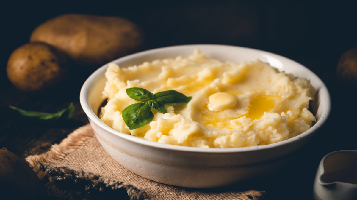 Mashed potatoes with butter in a white bowl on wooden rustic table.