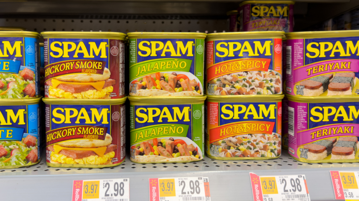 Cans of Spam in variety of flavors on supermarket shelf.