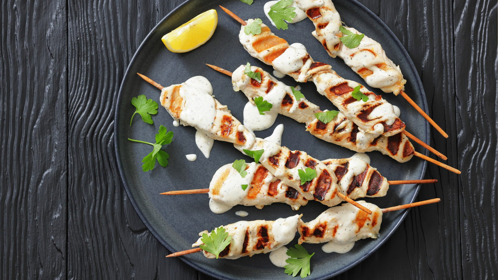 Greek style grilled chicken souvlaki on wood sticks drizzled with yogurt