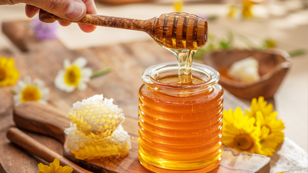 Natural organic honey in glass jar, honey dipper and honeycombs