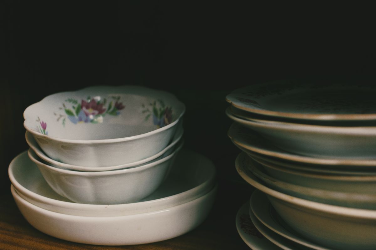 A close-up of floral bowls and dishes stacked inside a dark cupboard.