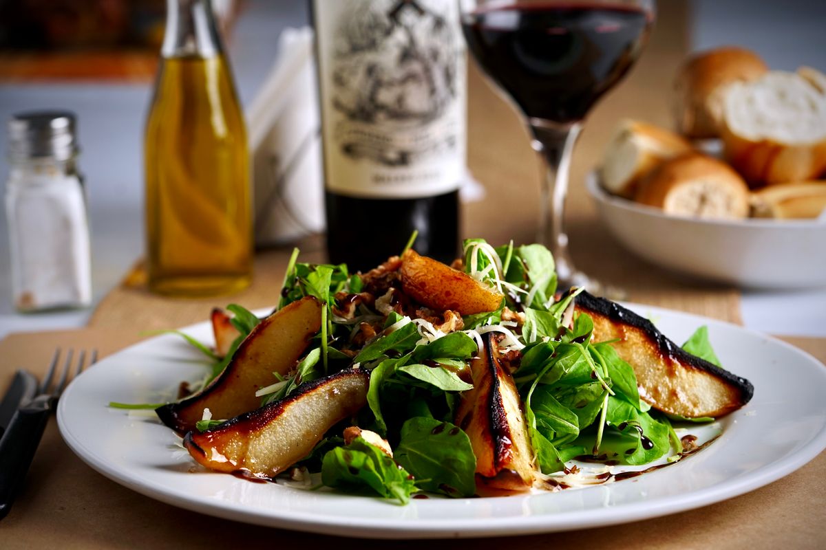 A delectable pear salad paired with red wine and bread for an elegant dining experience.