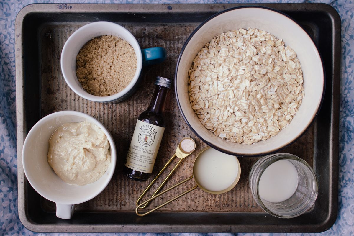 A flat lay of ingredients for oatmeal cookies, including oats, brown sugar, and vanilla.