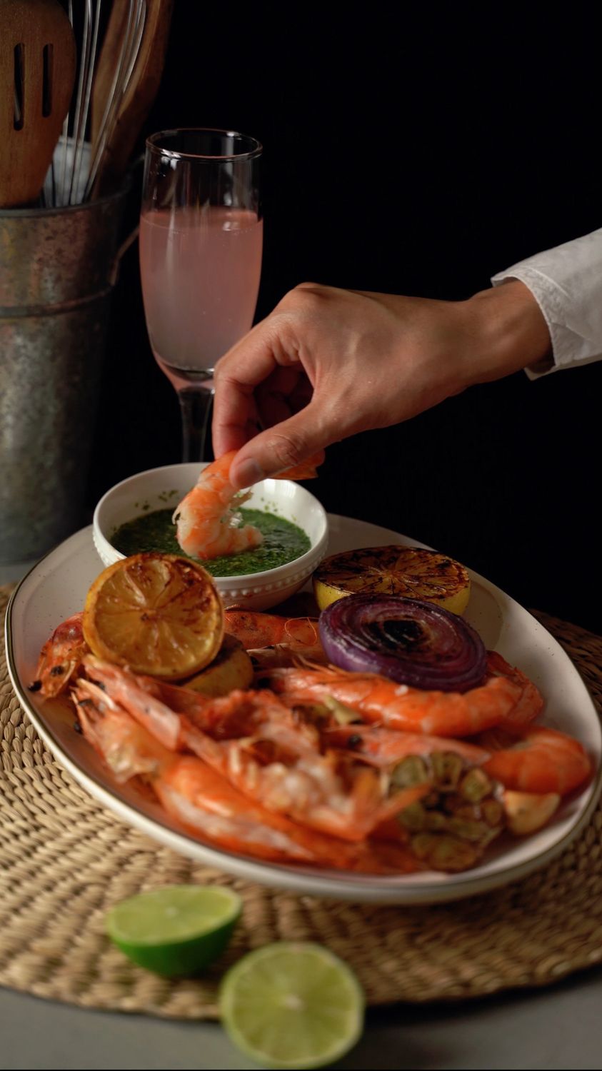 A hand dips a prawn into sauce on a gourmet seafood platter.