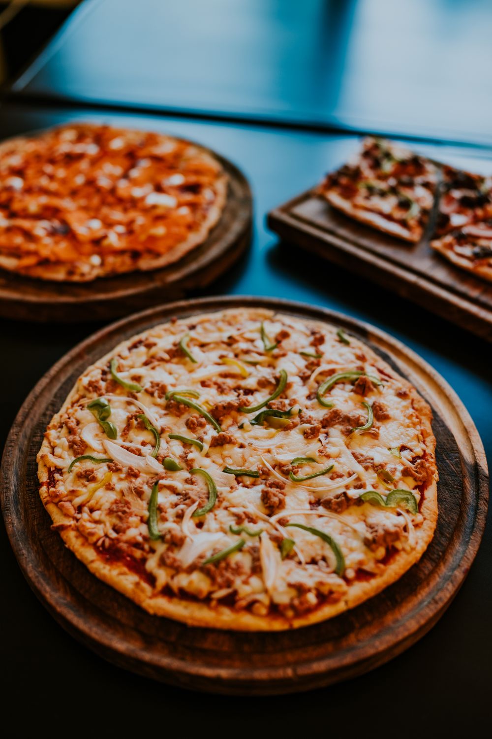 A mouthwatering display of freshly baked pizzas with various toppings on wooden trays.