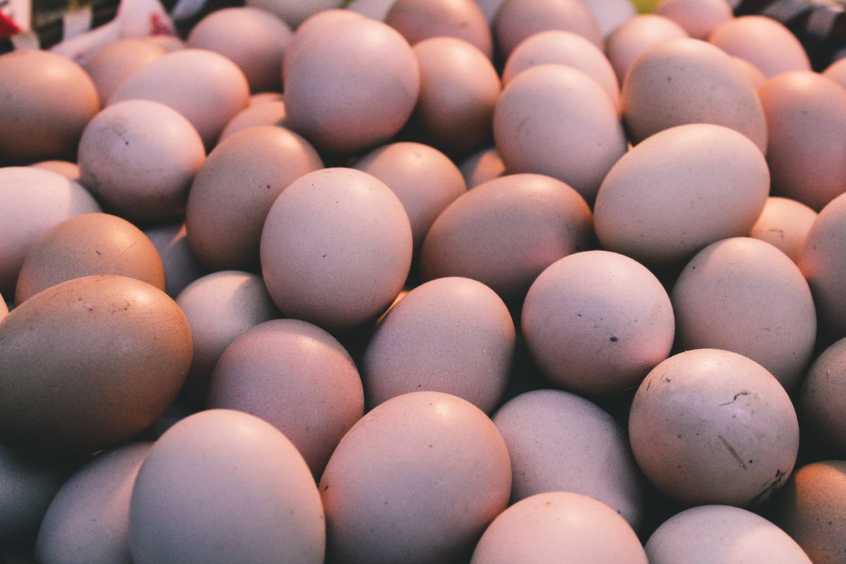 A pile of fresh brown eggs in a warm-lit market setting, showcasing natural textures.