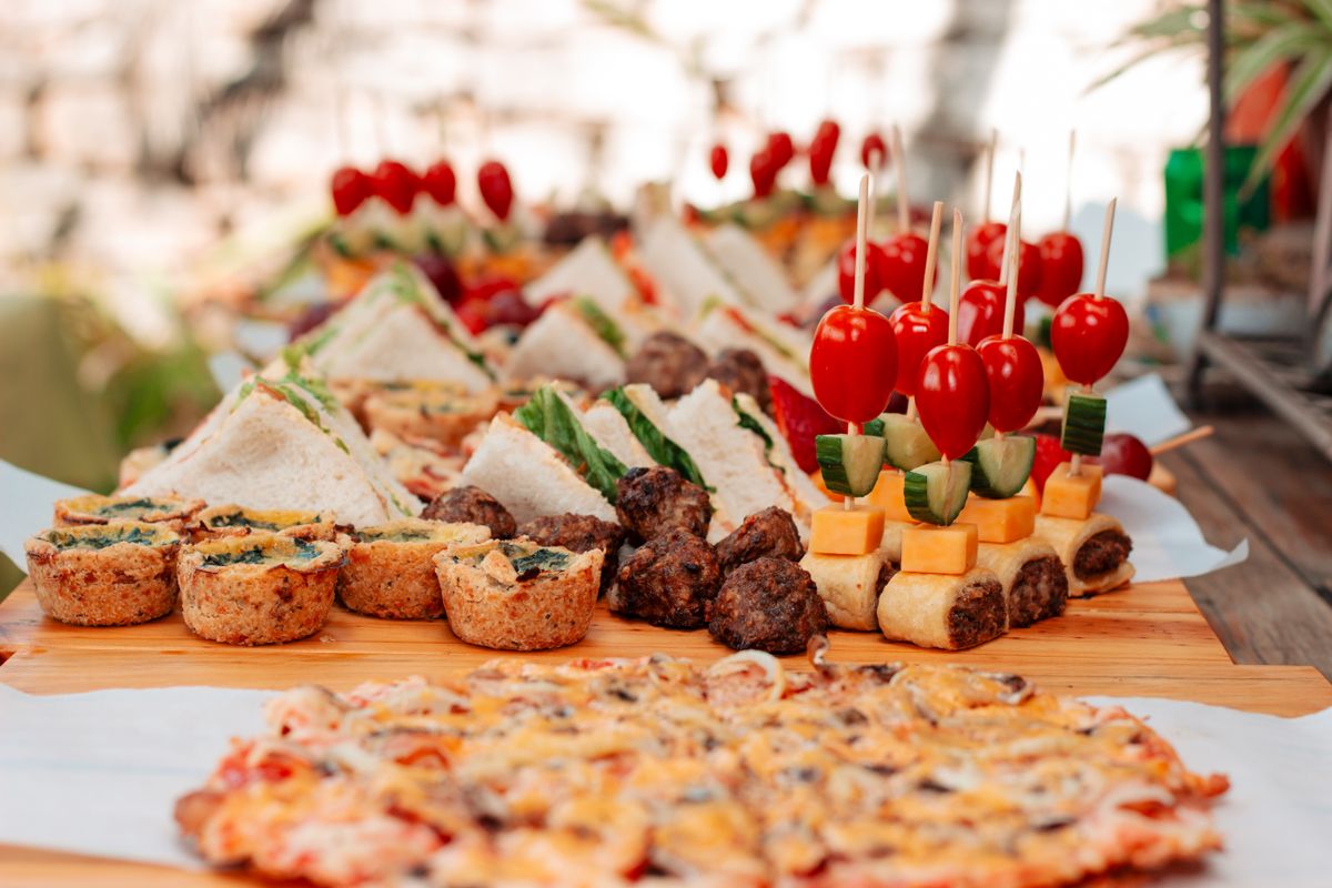 A tasteful display of sandwiches, skewers, and pastries perfect for a garden party or picnic.