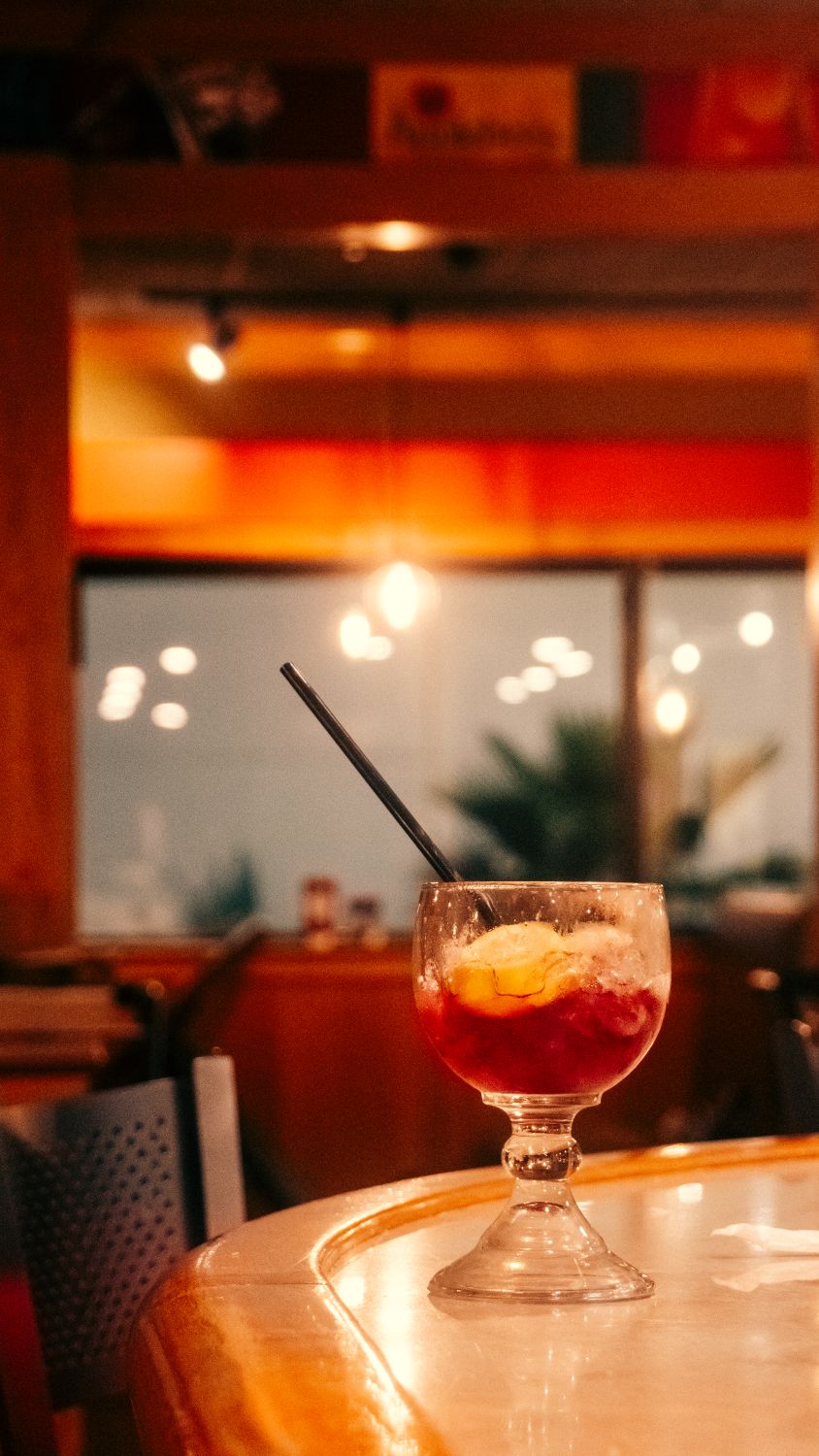 A warm Restaurant setting featuring a vibrant cocktail with fruit slice, perfect for relaxation.