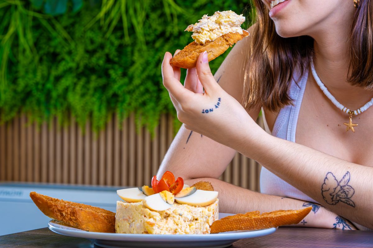 A woman enjoys a delicious homemade egg salad topped with tomatoes and bread.