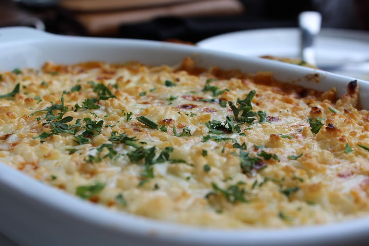Close-up of a golden baked casserole dish topped with herbs, perfect for a comforting meal.