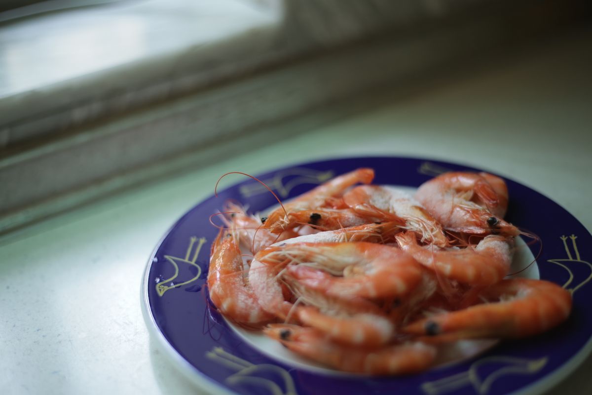 Close-up of fresh shrimp on a decorative plate by a window in soft light.