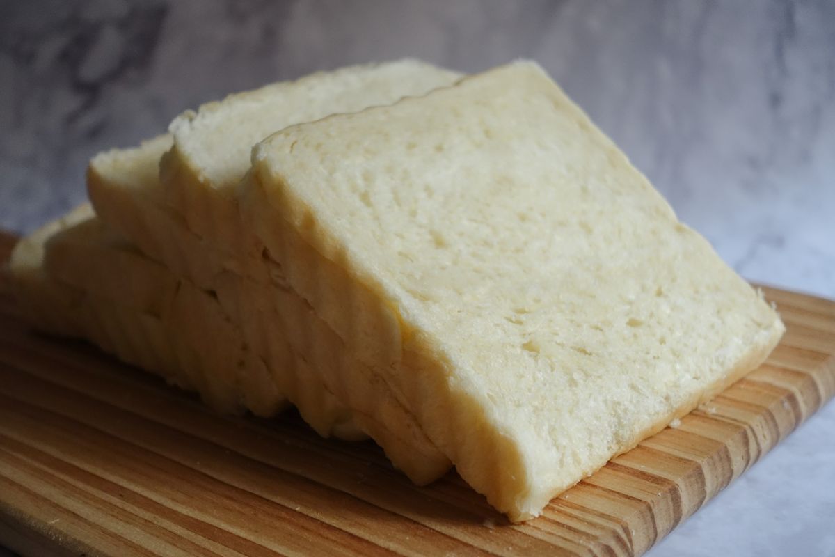 Close-up of freshly sliced white bread arranged on a wooden chopping board, perfect for culinary presentations.