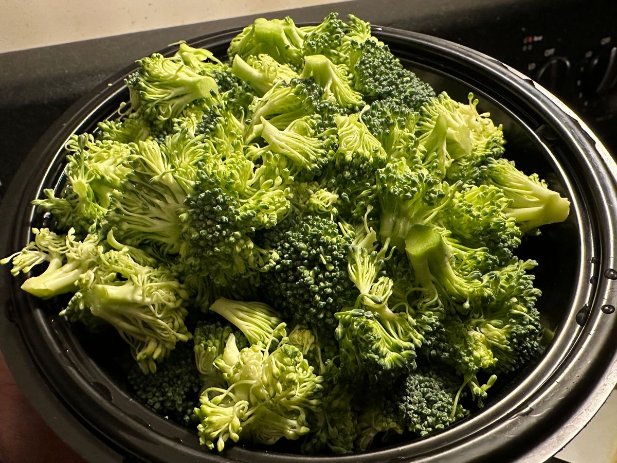 Close-up of vibrant green broccoli florets in a black pot, showcasing their freshness.