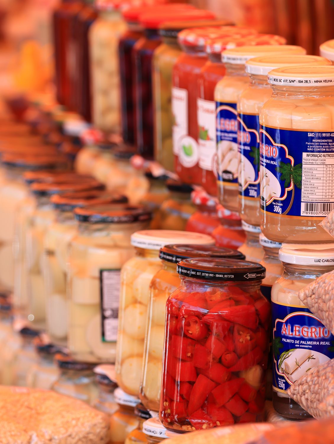 Colorful jars of preserved food neatly arranged in a vibrant market setting.