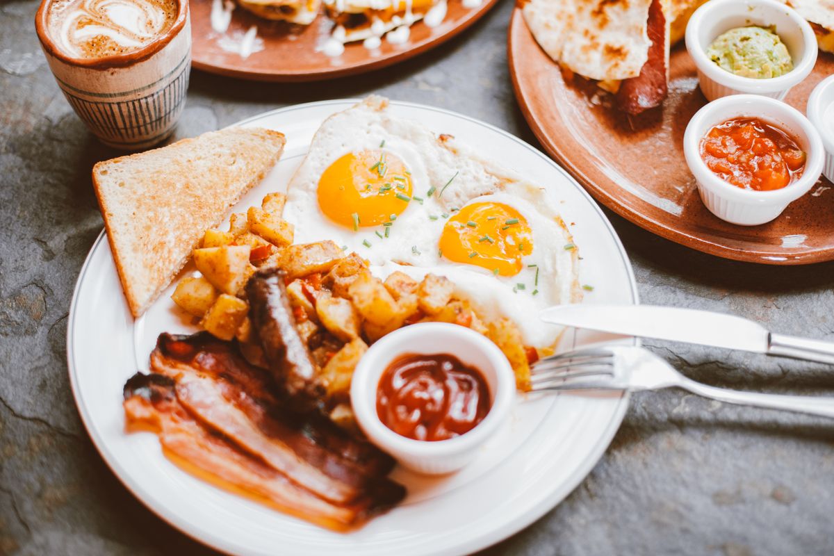 Delicious breakfast with sunny side up eggs, bacon, toast, and coffee.