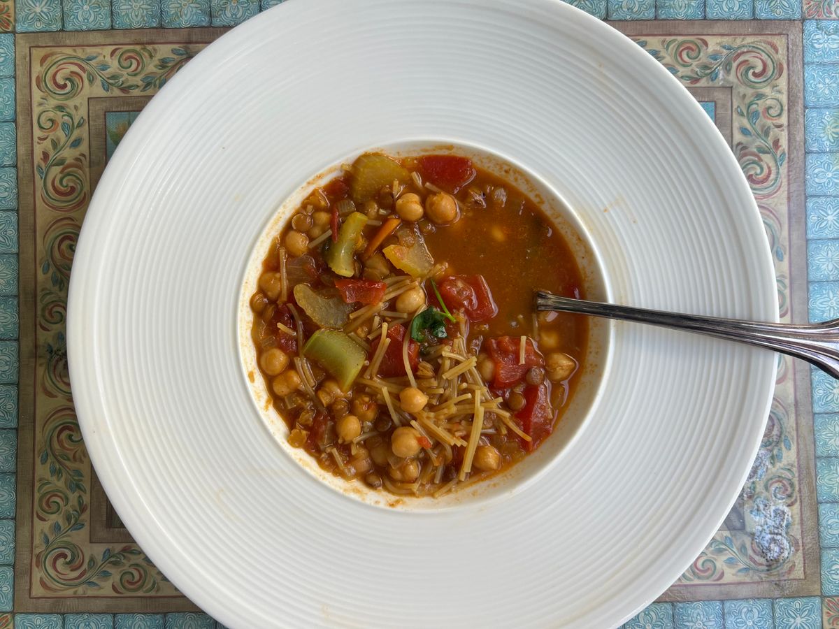 Delicious chickpea soup served in a white bowl on a decorative placemat.
