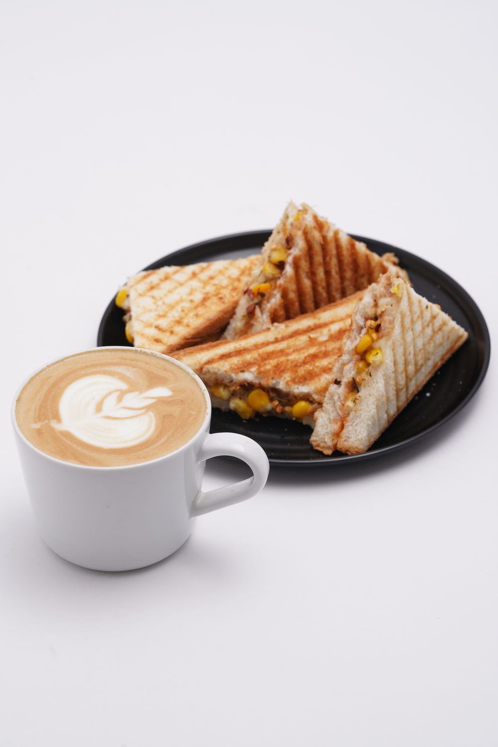 Delicious grilled sandwiches served with a latte featuring beautiful latte art on a white background.