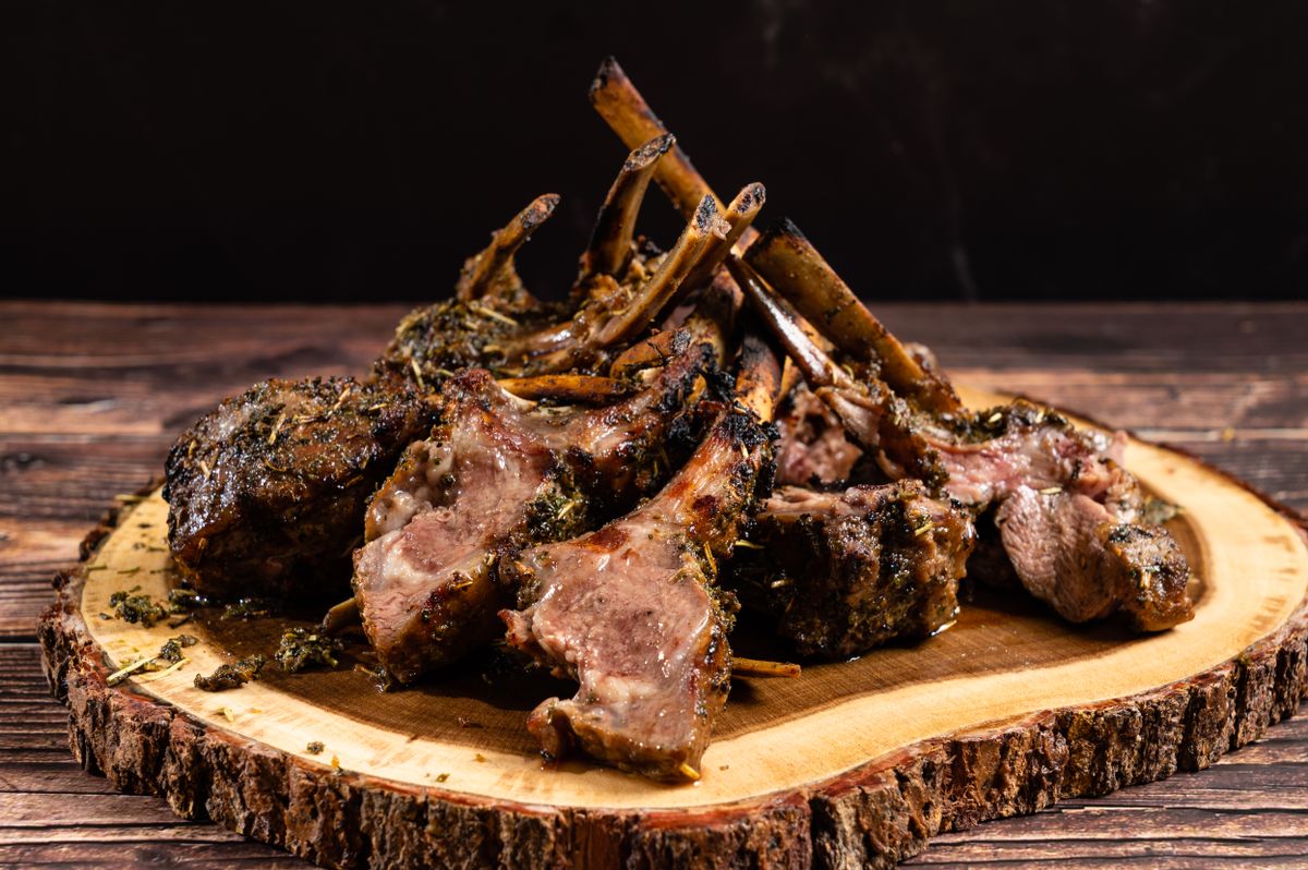Delicious herb-crusted lamb chops on a rustic wood platter, perfect for elegant dining.