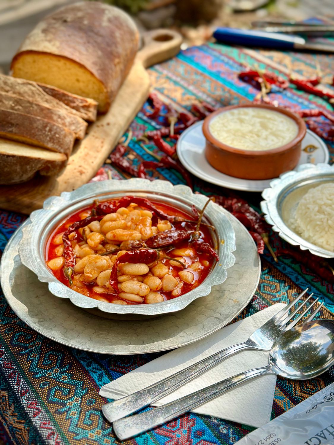 Delicious homemade bean stew served with sliced bread on a colorful patterned tablecloth.