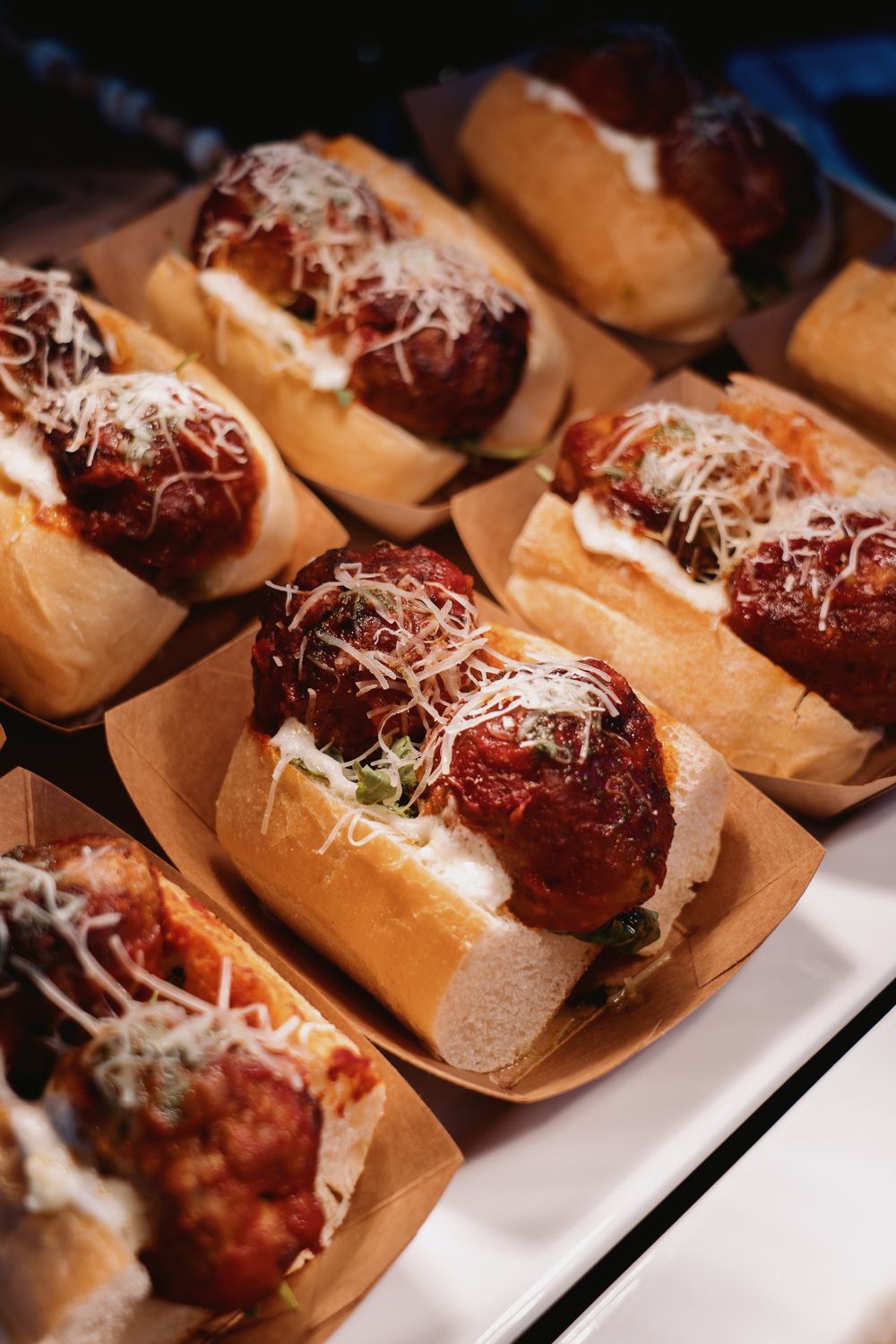 Delicious meatball subs topped with fresh grated cheese and herbs, perfect for a savory meal.