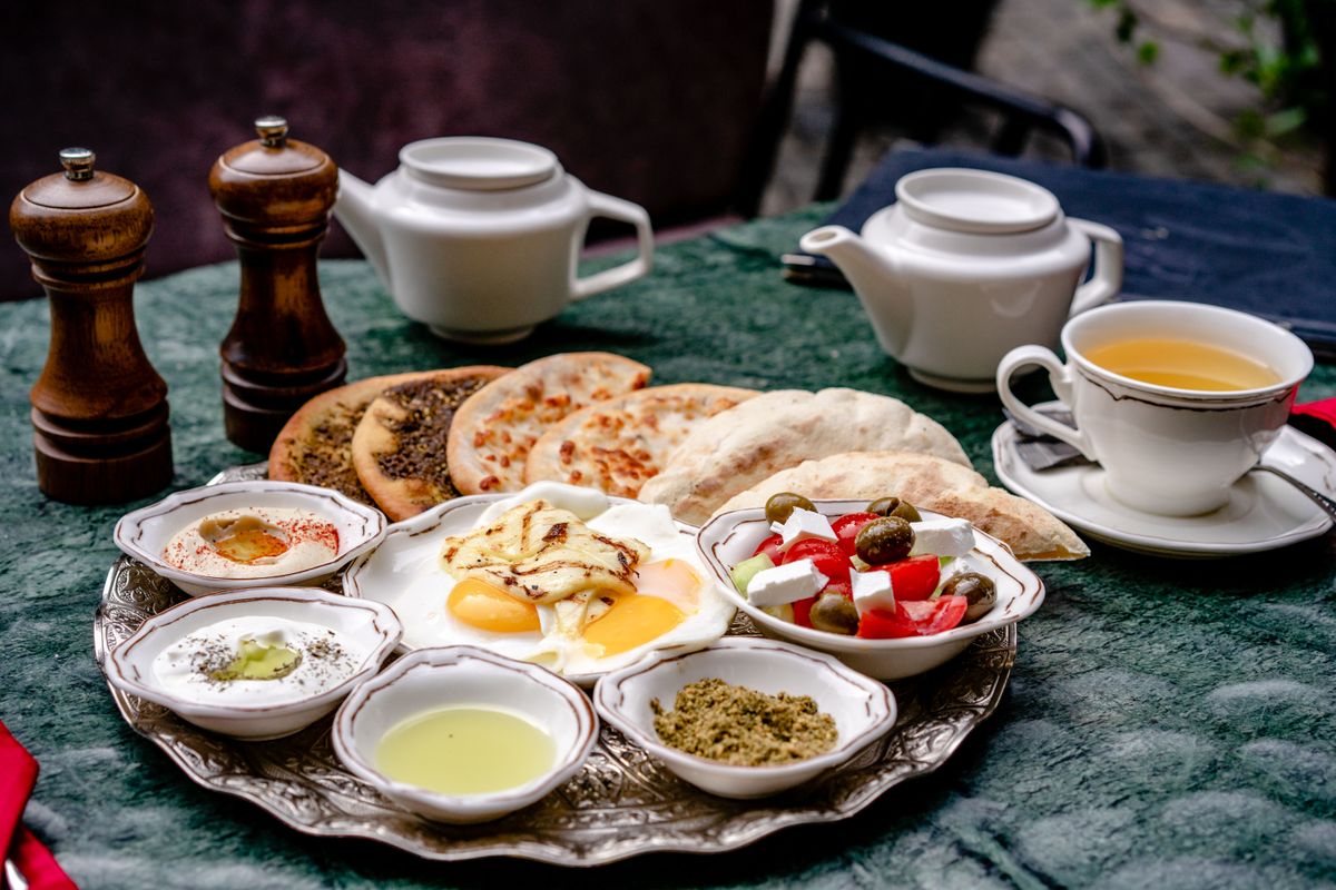 Delicious Middle Eastern breakfast featuring sunny-side-up eggs, tea, and various dishes.