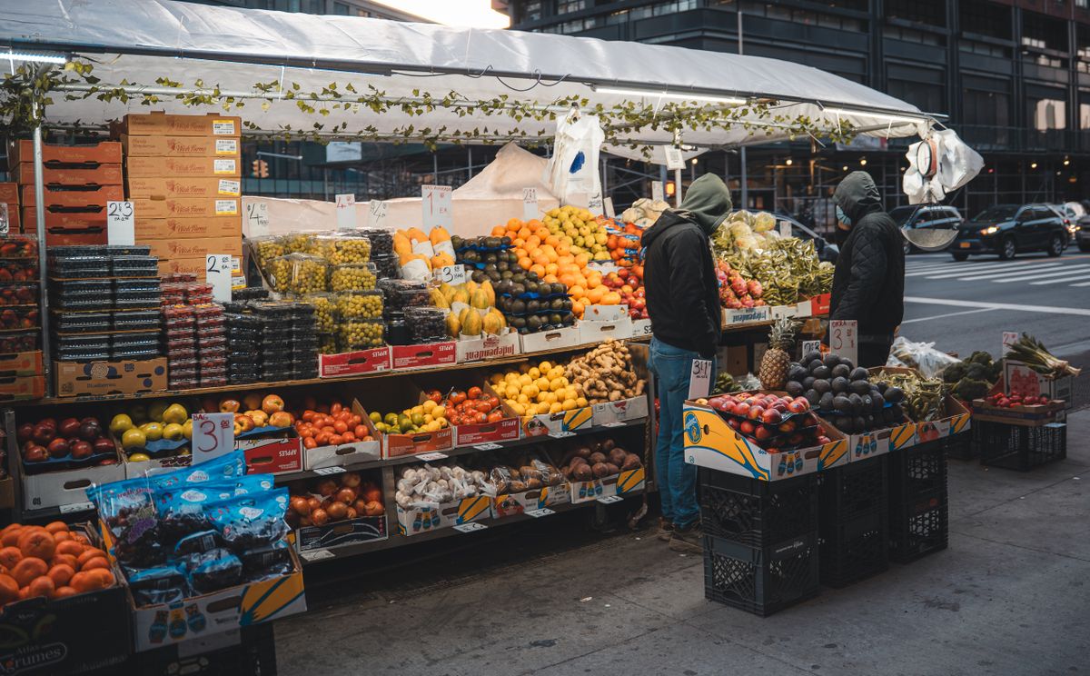 Fresh fruits and vegetables at a bustling street market in New York City during daytime.