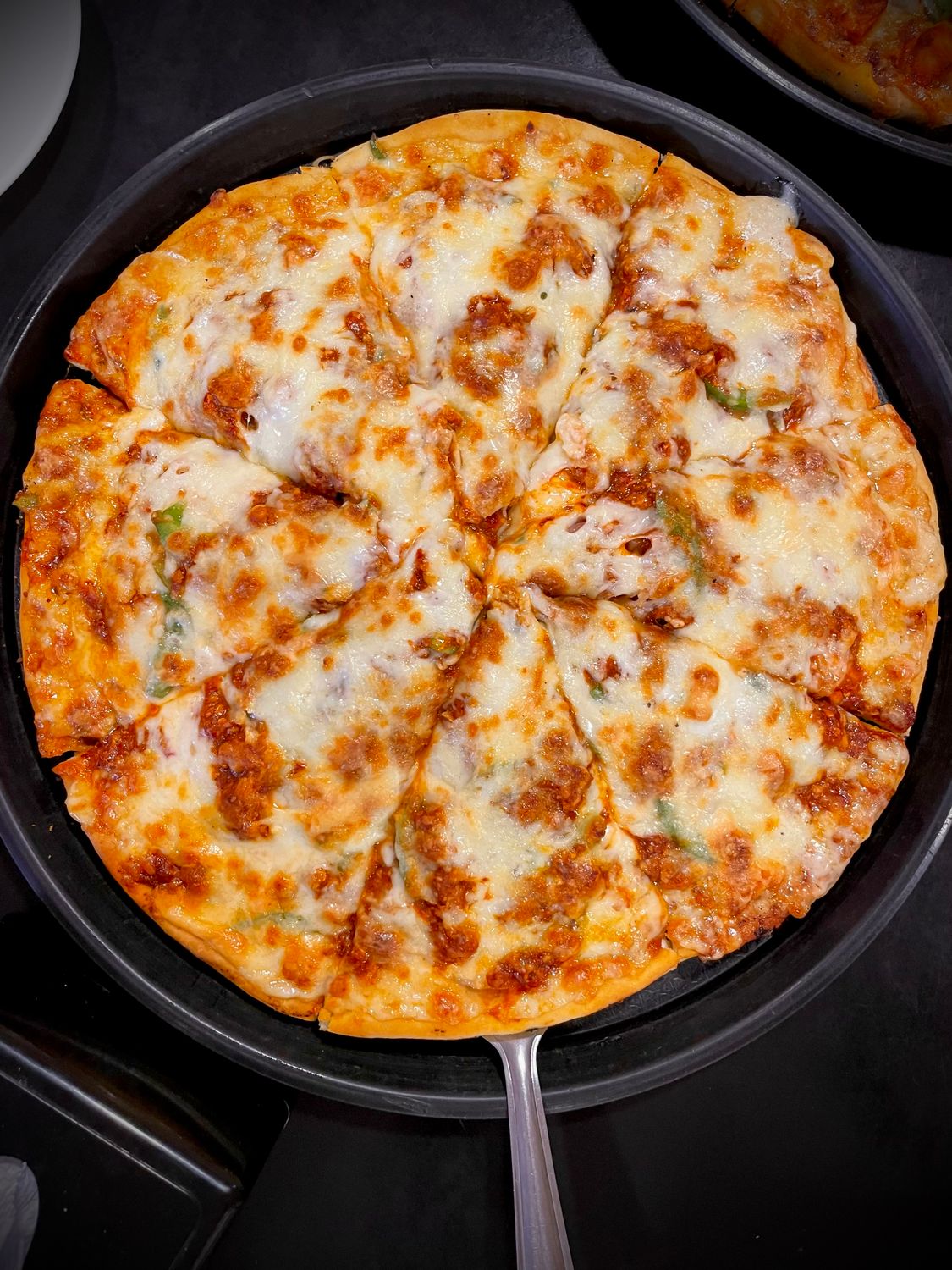 Fresh pizza with melted cheese and toppings in a pan, viewed from above - ideal for food enthusiasts.