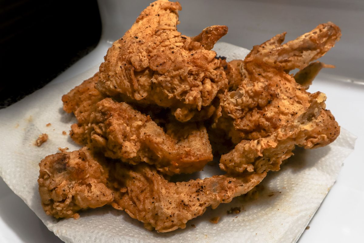 Golden brown fried chicken wings on a paper towel, showcasing a delicious, crispy texture.