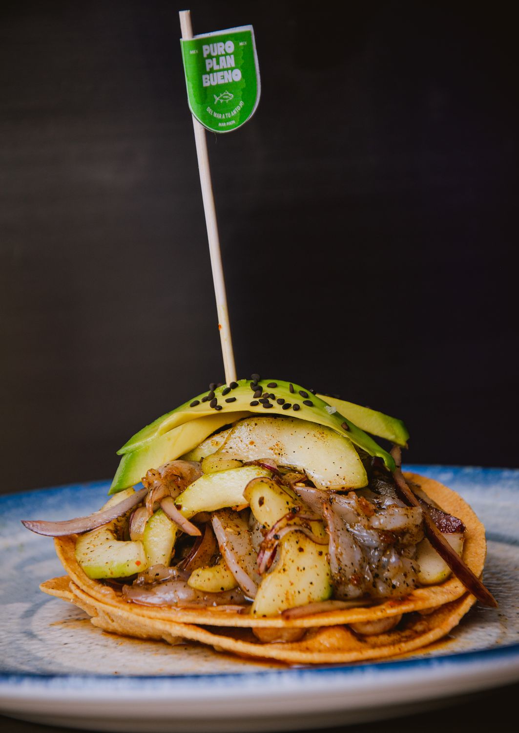 Gourmet dish featuring avocado, apple, onions, and sesame on crispy tostadas.