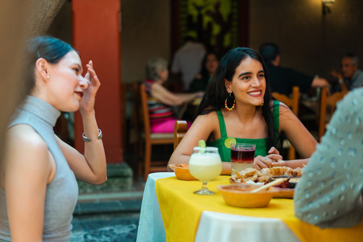 Where Dining Out Costs the Most and Least in America, From Burger Combos to Luxury Meals 1 Group of friends enjoying food and drinks at a Mexican restaurant, capturing a lively and festive atmosphere outdoors.