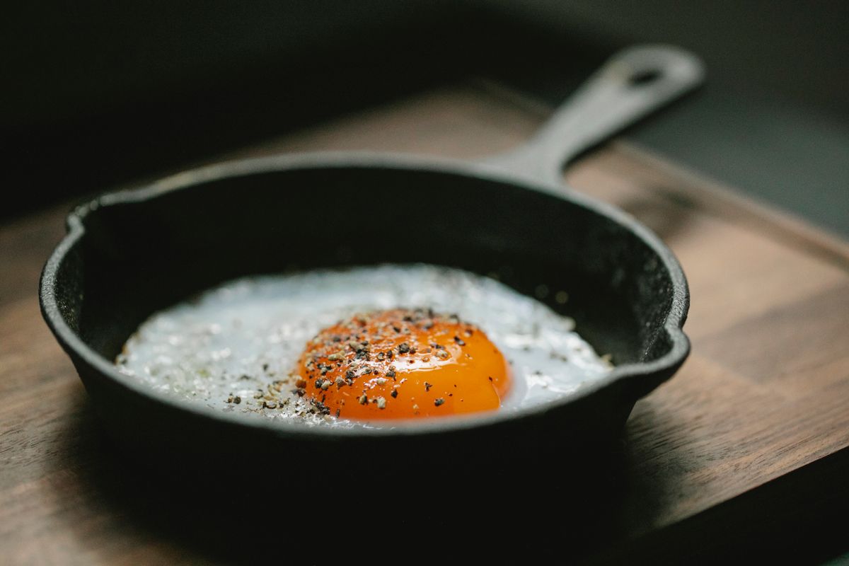 8 Easy Recipes for Students and Solo Dwellers: Simple Meals That Save Time, Money And Stress. 1 High angle of pan with fried egg with seasoning placed on wooden board in kitchen