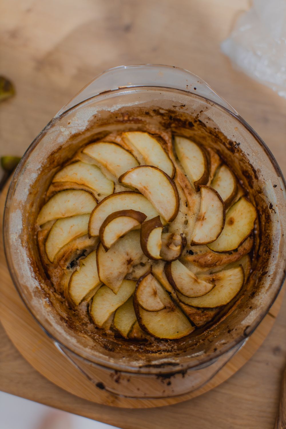 Overhead view of homemade apple tart in glass baking dish on wooden table.