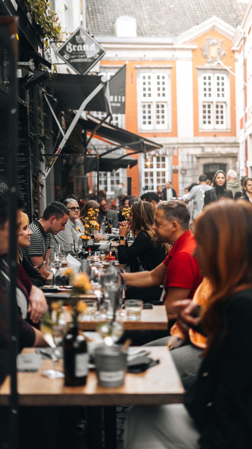 People enjoying al fresco dining at a bustling street restaurant in Maastricht, Netherlands.