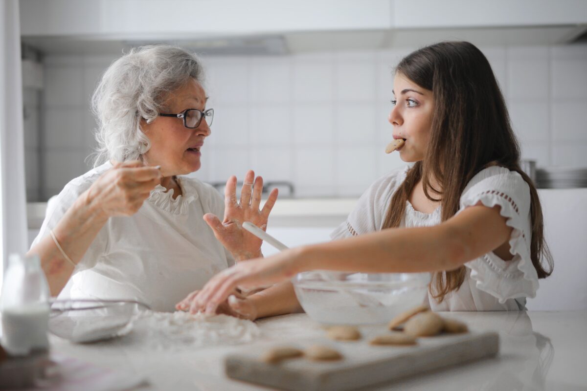 pensive-grandmother-with-granddaughter-having-interesting-conversation-while-cooking-together-in-light-modern-kitchen-3768146/