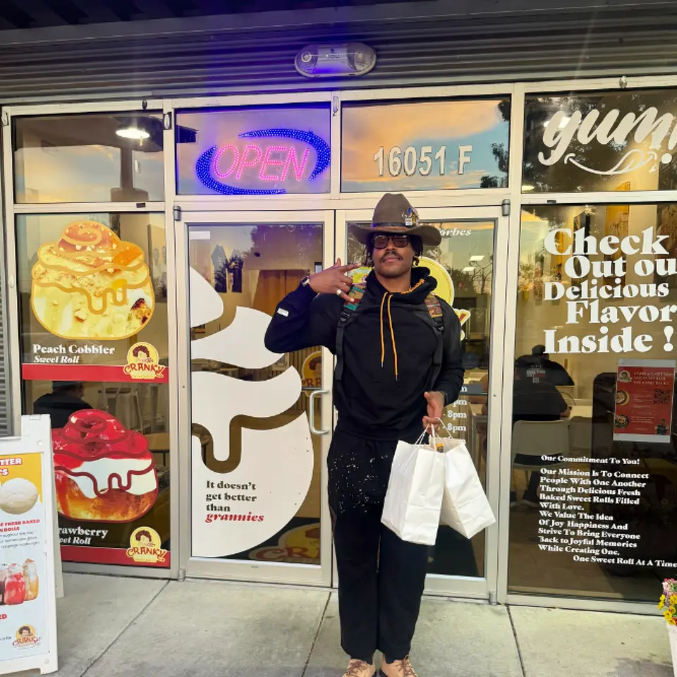 Cam Newton poses for a photo with his bag of cinnamon rolls at Cranky Granny's in Pflugerville, Texas.