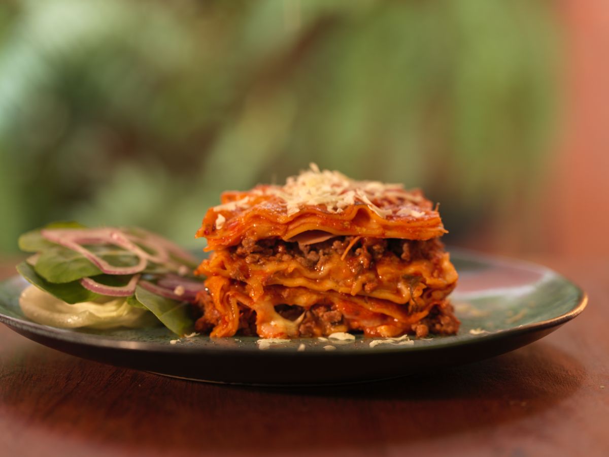 Savor a freshly prepared lasagna with cheese and meat filling, garnished with salad.