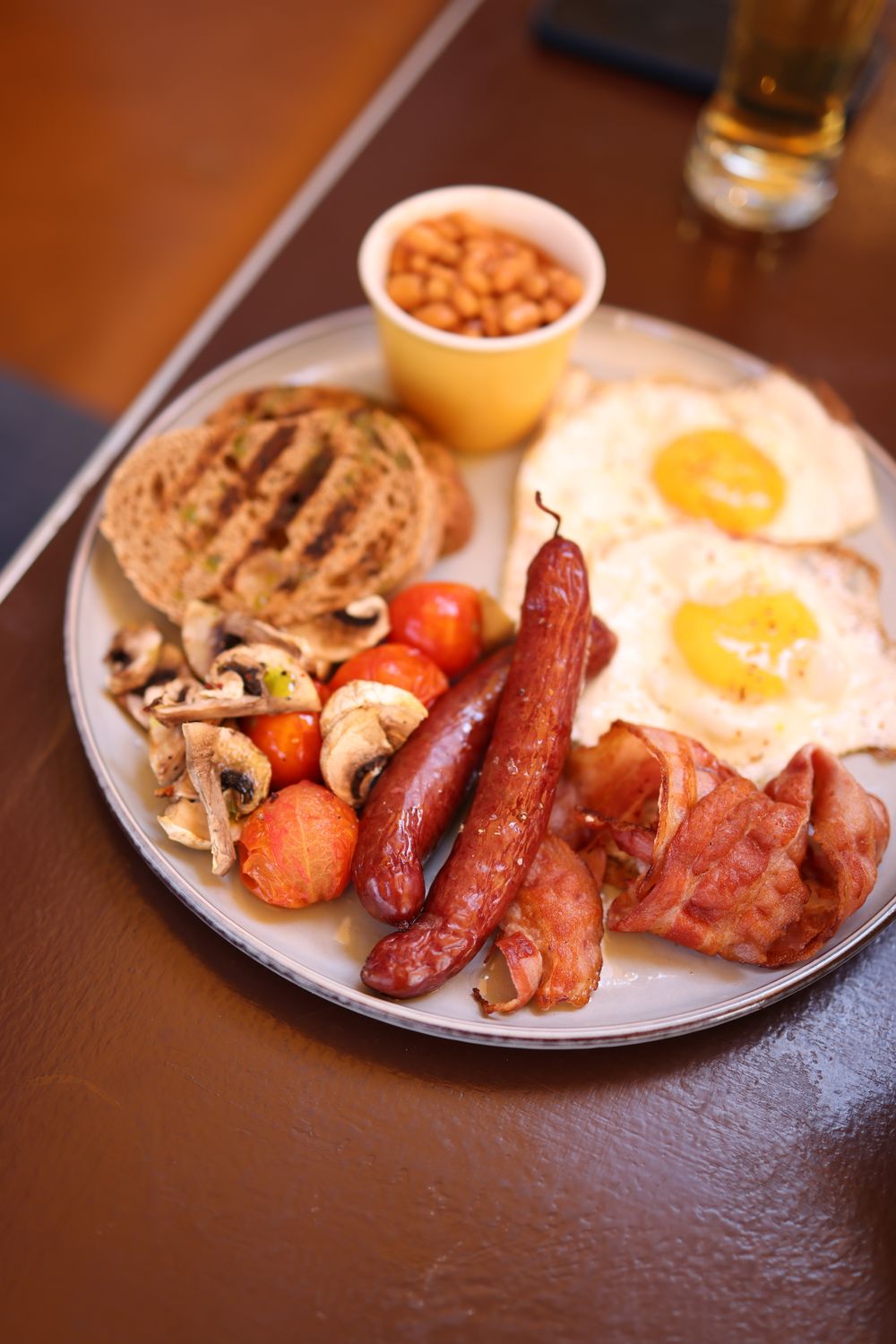 Savoury English breakfast featuring eggs, sausages, bacon, and more, beautifully plated.