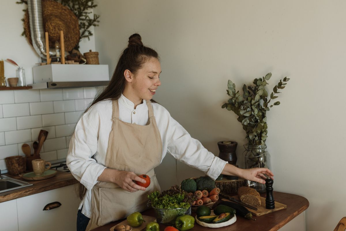 Texas Farmers Market Shoppers Beware: 6 Foods You Should Never Store Together (They Spoil Faster) 1 Smiling woman in apron preparing a meal with fresh vegetables in a cozy kitchen.
