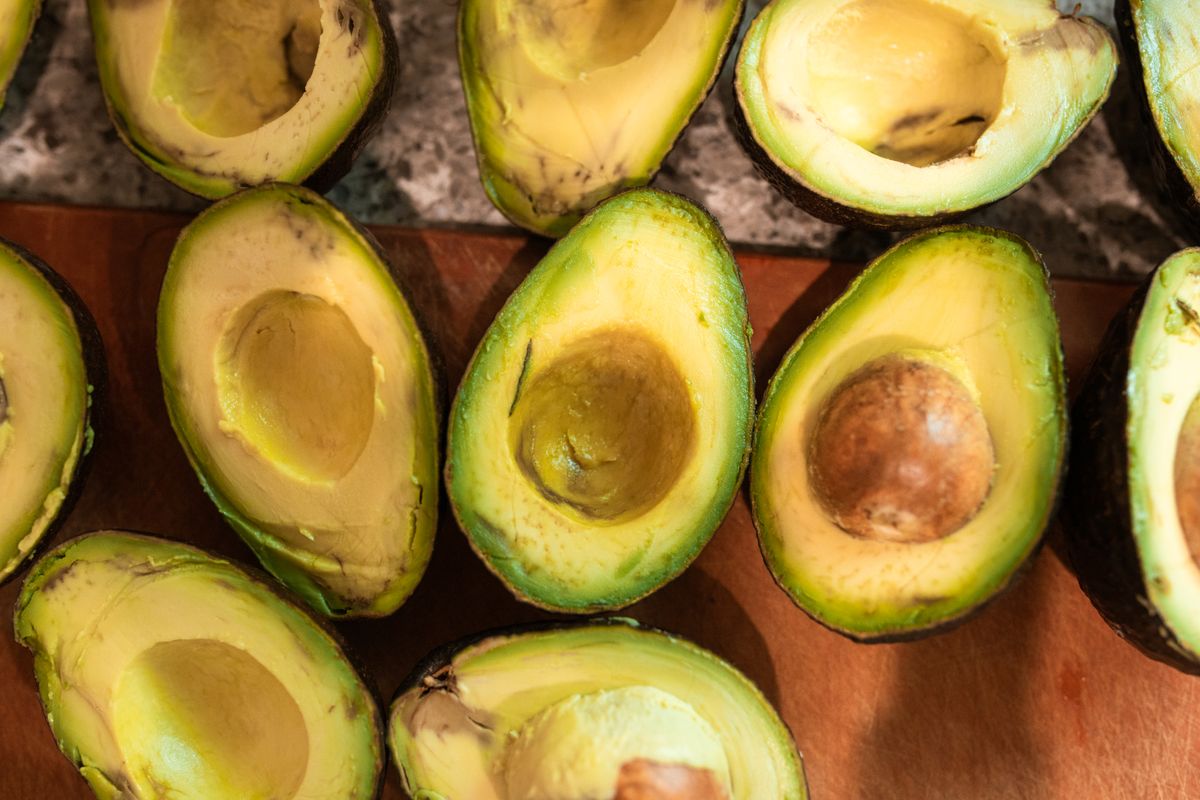 5 Signs an Avocado Has Gone Bad 1 Top view of halved ripe avocados on a wooden surface, showcasing freshness and texture.