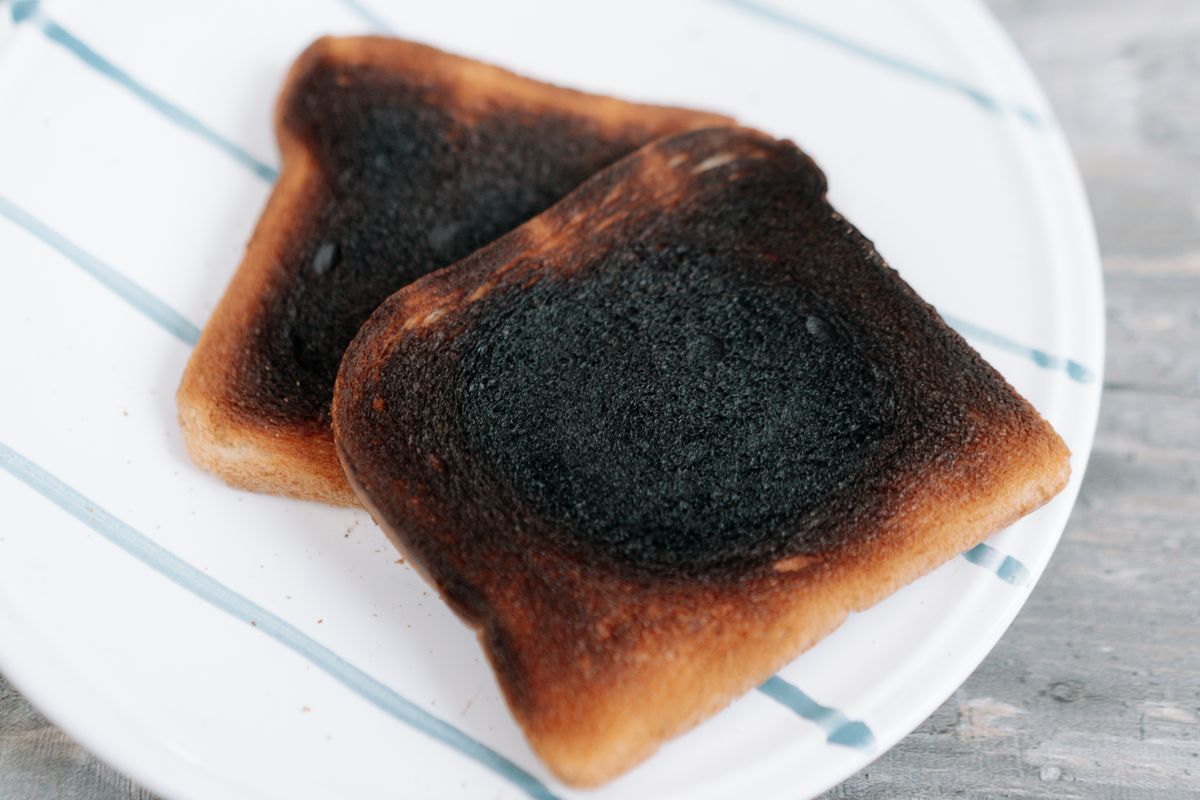 Two slices of burnt toast served on a white ceramic plate, perfect for breakfast or food concepts.