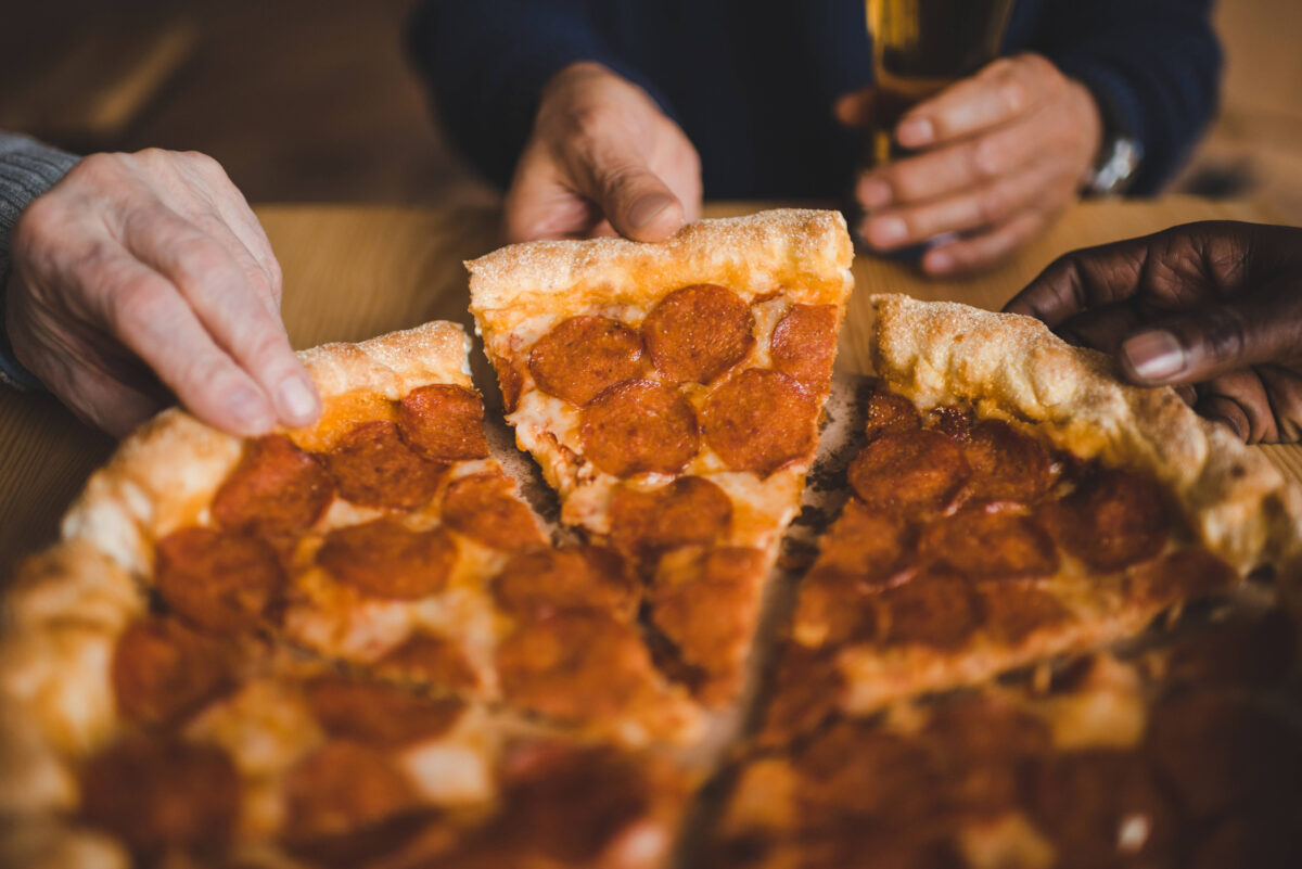 cropped shot of people taking pieces of pizza