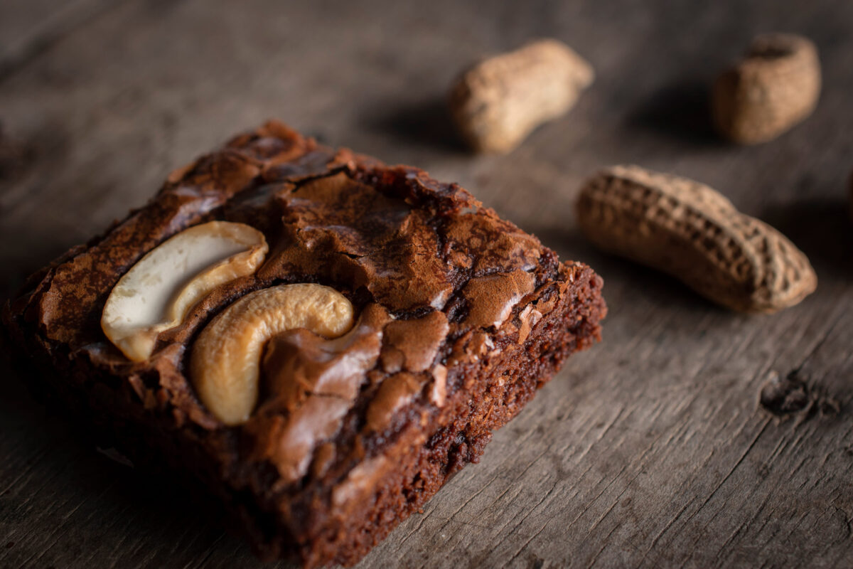 Brownie with topping Cashew Nut and peanuts put on back side. They are putting on a wooden desk.