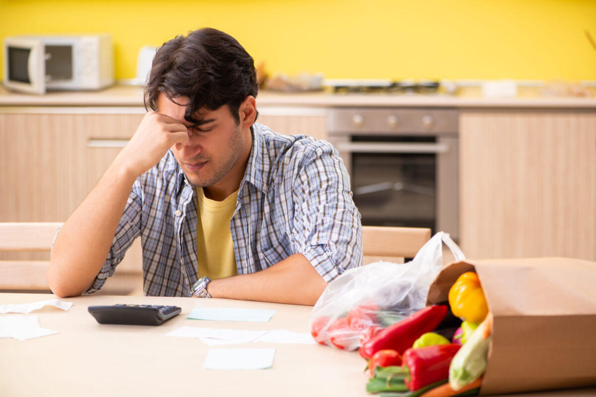 Young man calculating expences for vegetables in kitchen