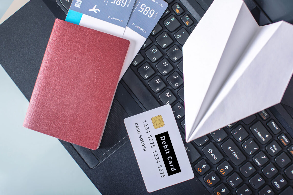 10 Expenses Couples Should Revisit After Retirement to Avoid Wasting Money 3 Airline tickets, passport, debit card and paper plane are on the laptop keyboard. The concept of purchasing and booking online