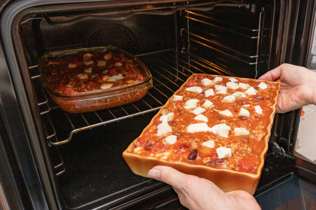 Preparing lasagna in a home kitchen. Cooking homemade meals for the household. Light background.