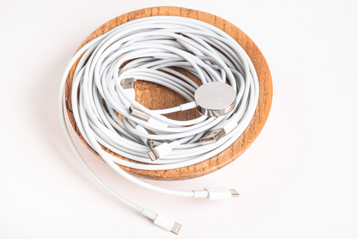 Vidalia, Georgia / USA - September 8, 2019: Several white Apple power cables and connectors swirling in a wooden bowl set on plain white background.