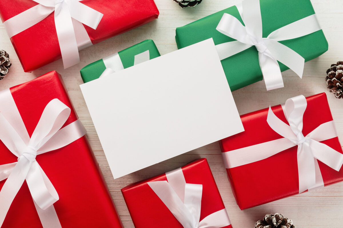 Christmas and new year with gift box wrapped with kraft brown paper and red ribbon on wooden table background top view.