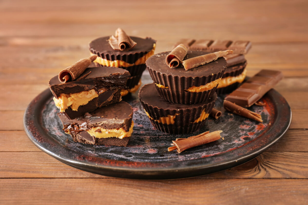 Plate with tasty chocolate peanut butter cups on wooden table