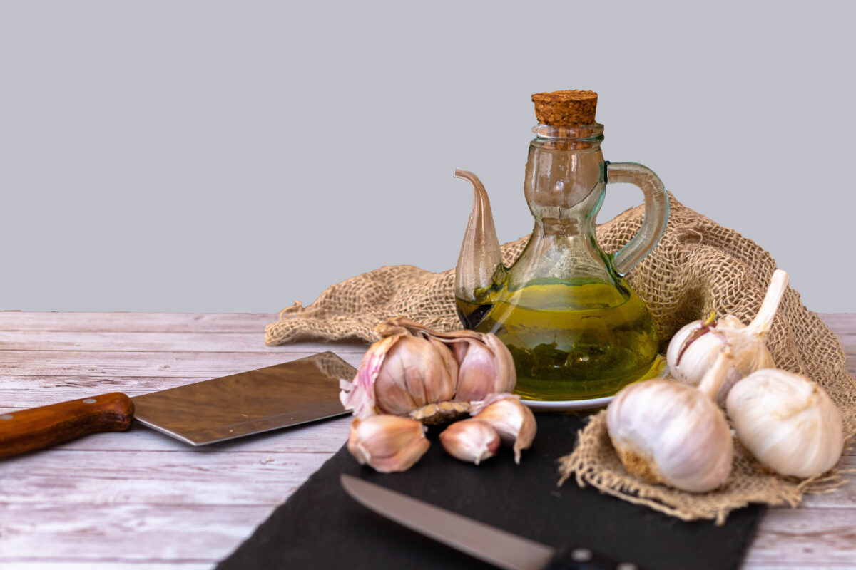 9 Things You Can't Legally Sell From Your Home Kitchen 4 Selective focus on a table with garlic and oil for the preparation of a golden liquid called garlic oil as a condiment on a gray background.