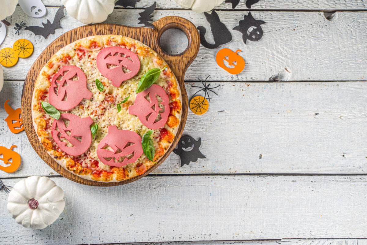 Halloween funny pizza. Halloween party recipe, Creative idea for Halloween pizza`s with ham and cheese ghosts, monster, spiders, white wooden background with Halloween decorations